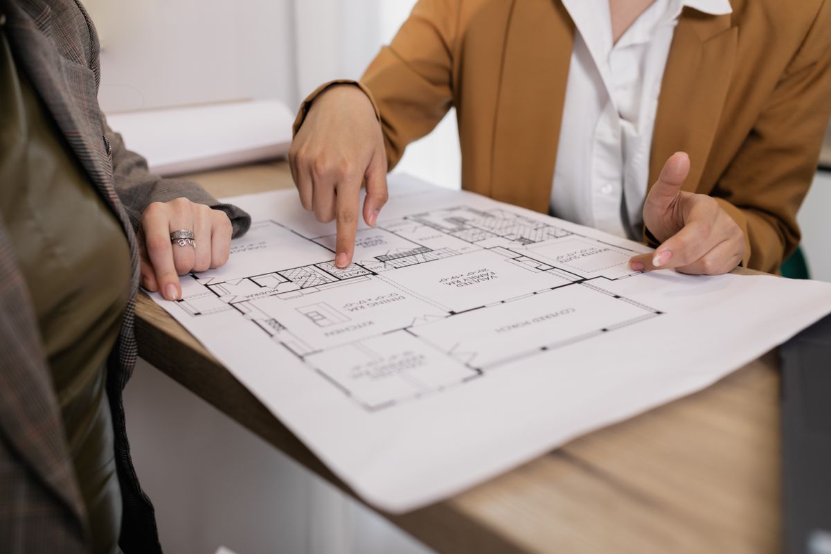 Two professionals reviewing a floor plan together at a table