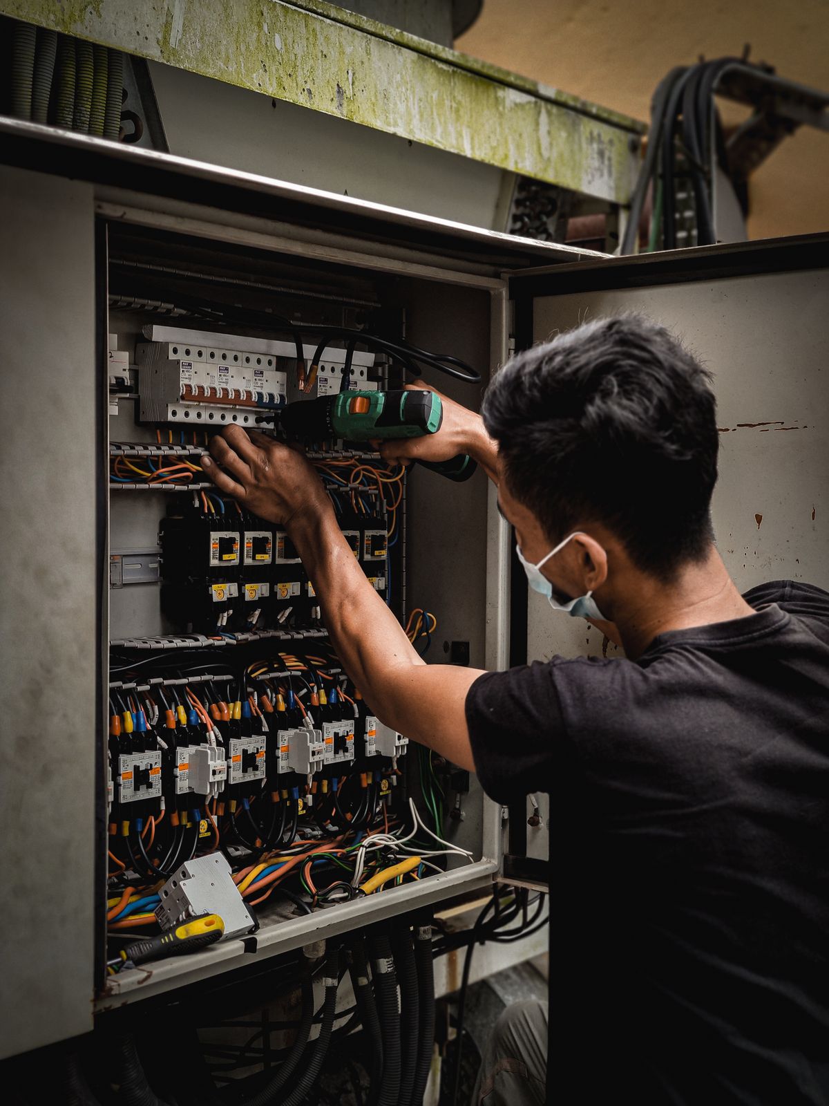 A technician working on the wiring inside an electrical panel