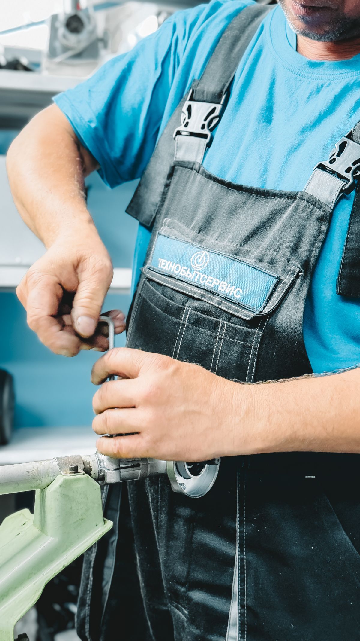 A plumber in overalls working on a pipe fitting with a wrench