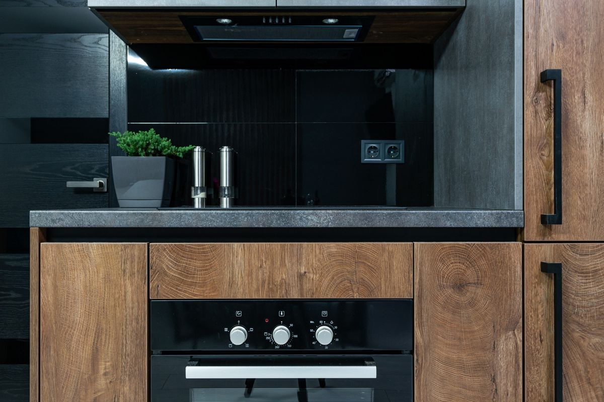 A modern kitchen with wood cabinets, black accents, and a built-in oven