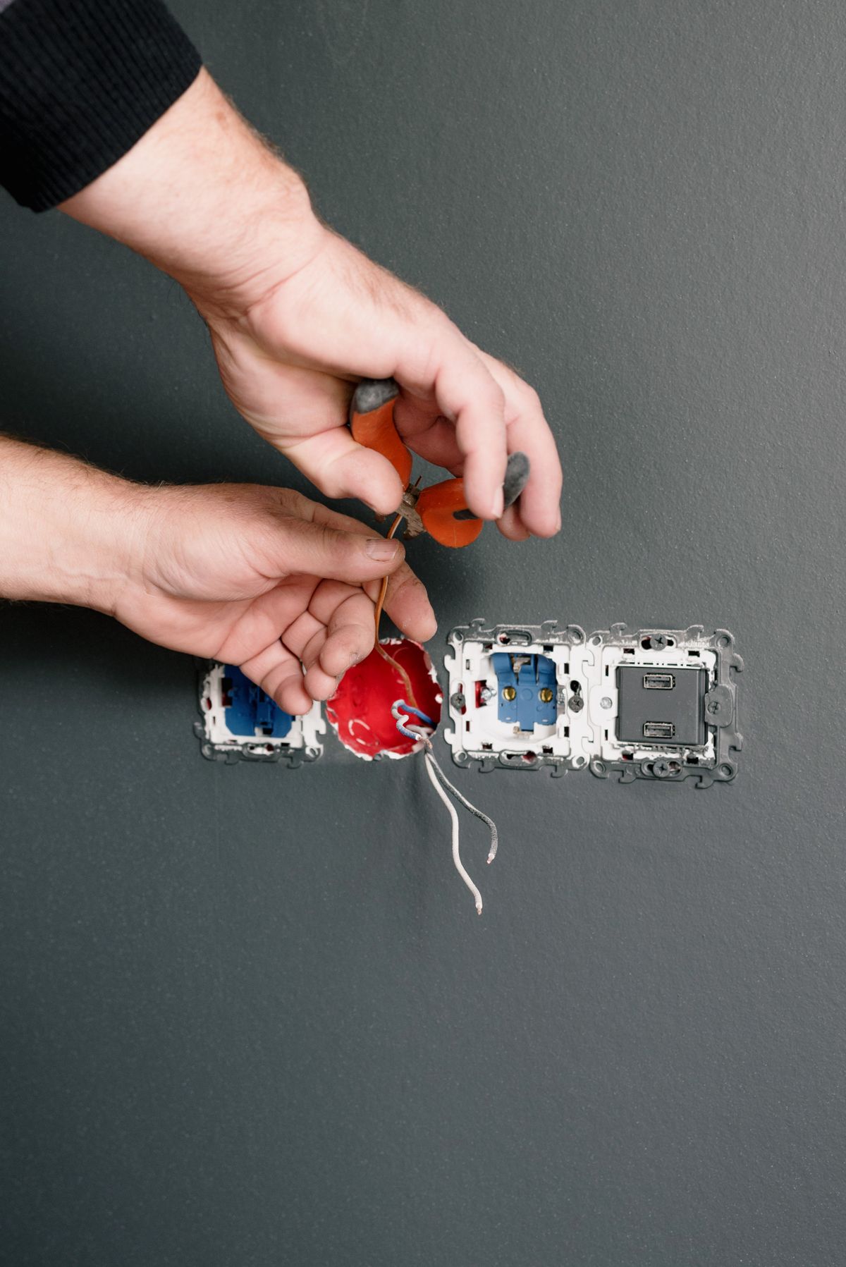 Hands wiring a wall socket with a screwdriver