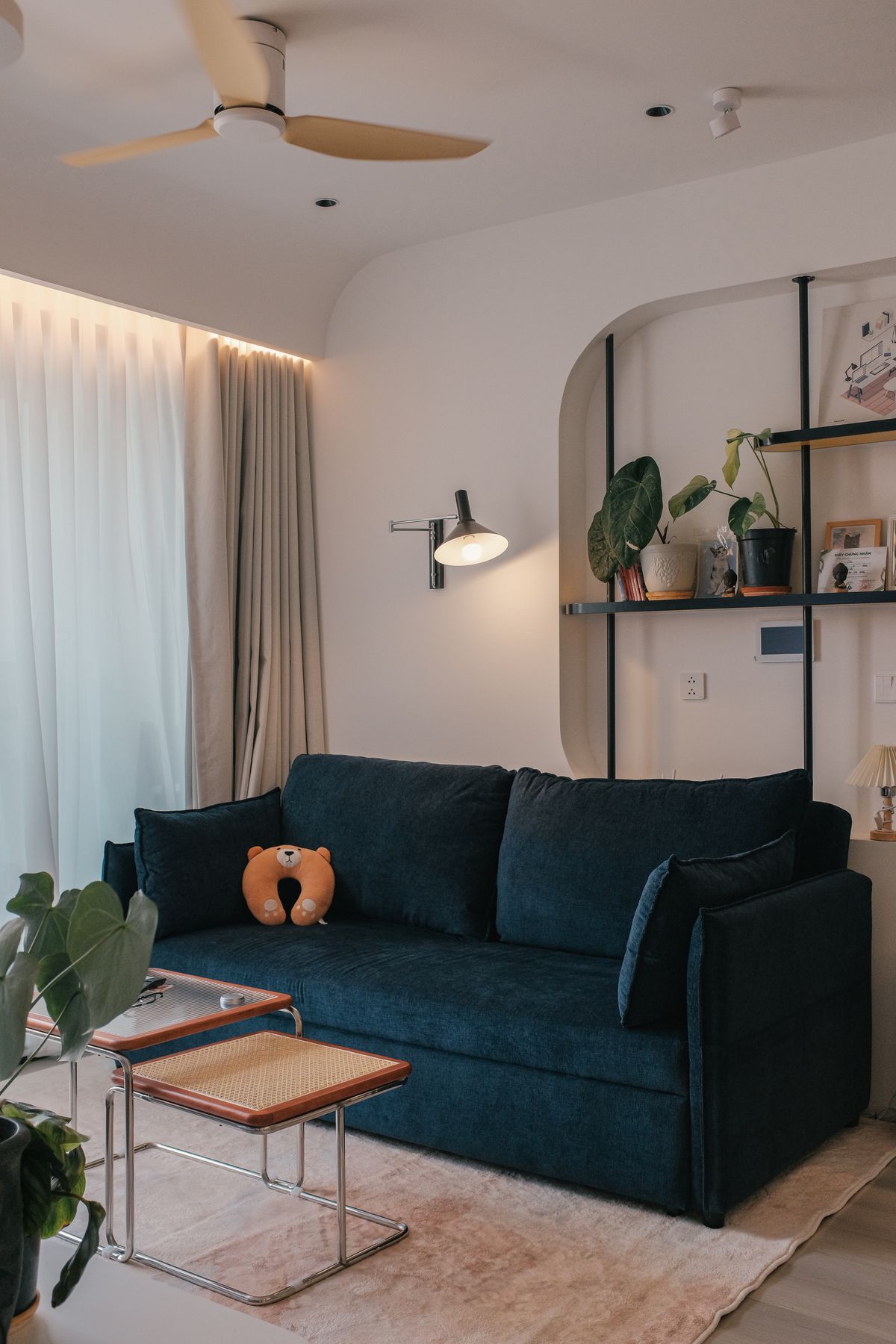 A stylish living room with a dark blue sofa and wooden tables