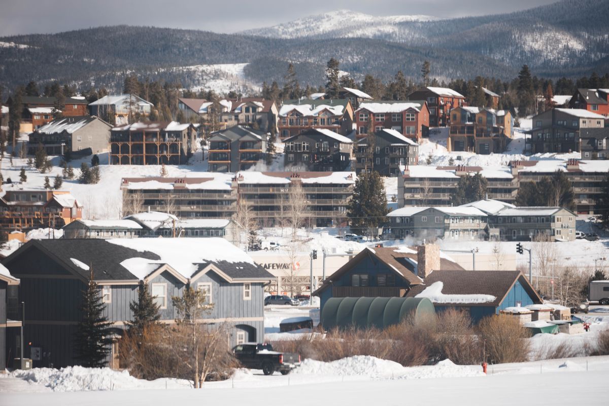 Snow-covered homes in a Colorado town with mountains behind