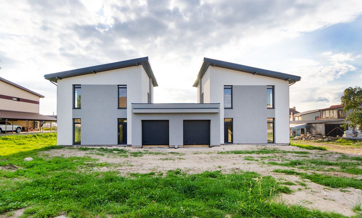 Two modern white houses with dark roofs on a grassy lot